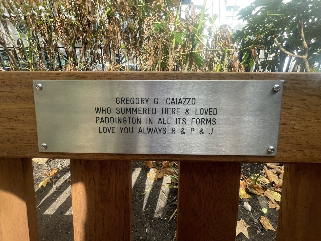 Close view of the plaque on Gregory G. Caiazzo's memorial bench in Norfolk Square Gardens, Paddington, London